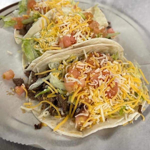 Three Burger Taco soft tacos filled with ground beef, shredded lettuce, diced tomatoes, and cheese.