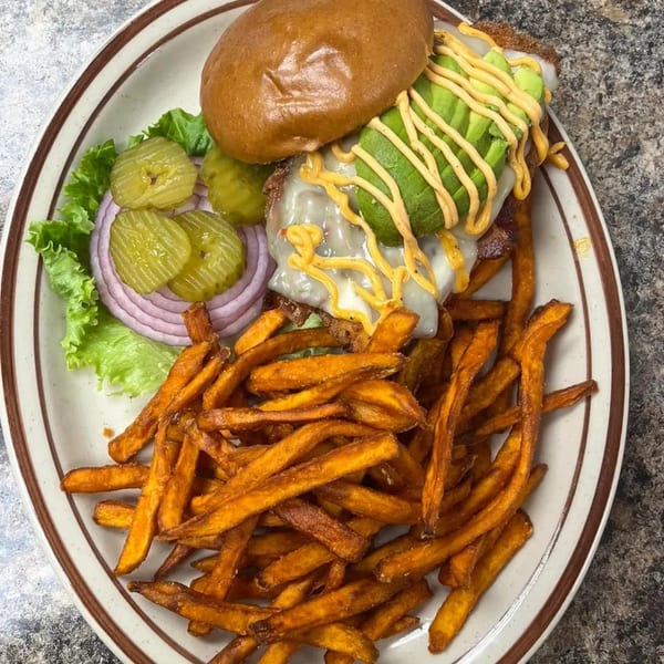 Burger Taco's avocado burger with melted cheese, lettuce, onions, pickles, and a side of sweet potato fries.